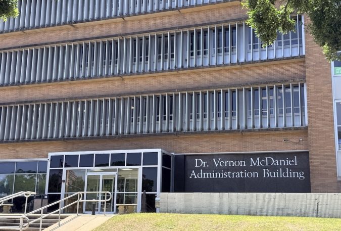 Front view of Dr. Vernon McDaniel Administration Building entrance with glass doors and metal railings.