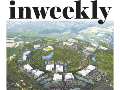 Inweekly magazine cover with an aerial view of a circular, campus-like development set in greenery and water; headline reads 'The Bluffs Could Trigger Job Boom'.