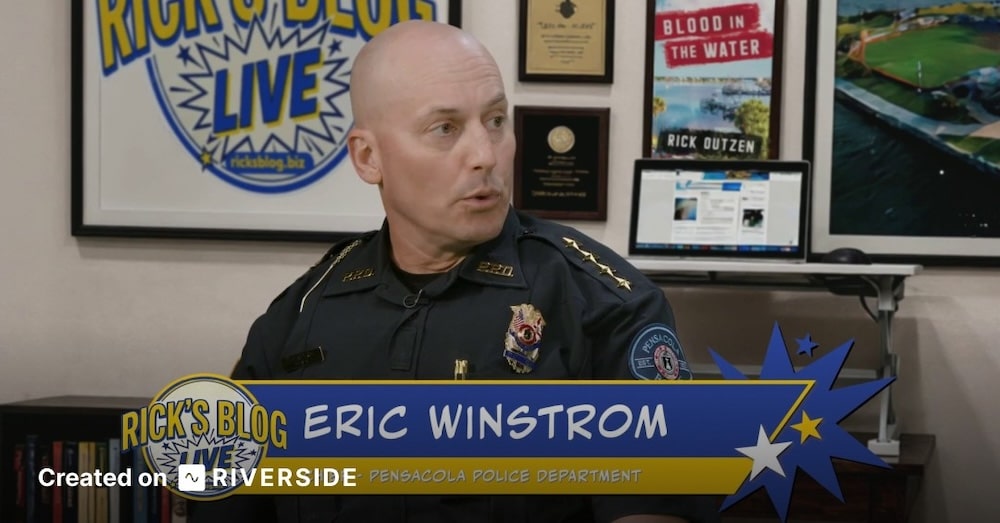 Bald Pensacola Police Department officer sits in a studio interview, with a blue-yellow banner reading 'Eric Winstrom' and 'Rick's Blog Live'.