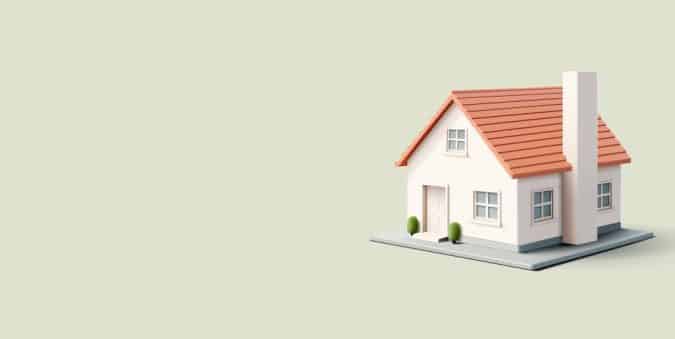 Model white house with a red gabled roof and chimney on a raised platform against a pale beige background