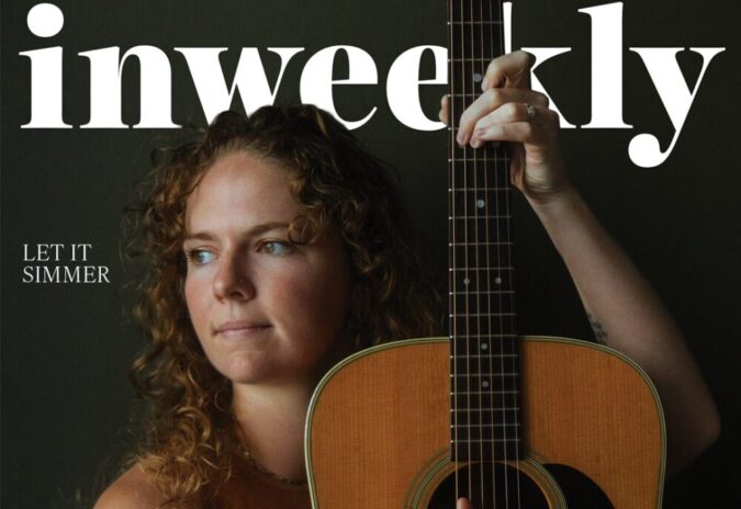 Portrait of a woman with curly hair holding an acoustic guitar, on a magazine cover with large 'weekly' text and 'Katie Dineen' featured